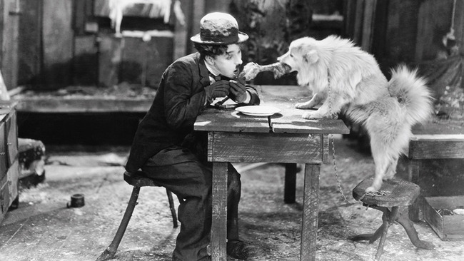 Charlie Chaplin and a dog sharing a bone in The Gold Rush (1925).